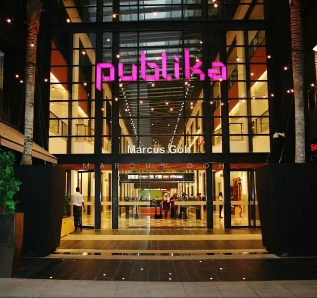 Exterior type: shopping mall; features: glass facade, illuminated signage, open entrance, paved walkway, palm trees, outdoor seating area, modern architectural design, high ceilings, interior lighting, large glass doors; style: modern.