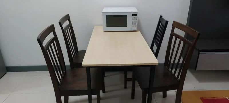 Dining features: rectangular dining table with light wood top, 4 wooden dining chairs with dark brown finish, microwave on the table, white walls, tile flooring, neutral color scheme; style: minimalist.