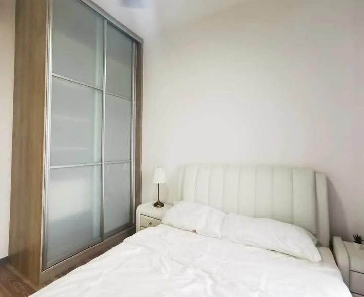 Bedroom features: king-size bed with white upholstered headboard, white bedding, nightstand with lamp, built-in wardrobe with sliding glass doors, wooden flooring, plain white walls, minimalist decor; style: modern.