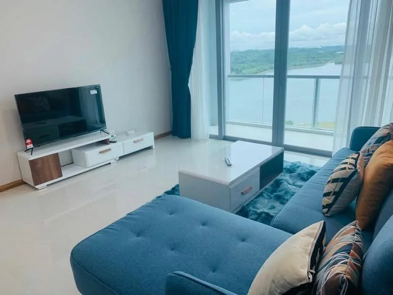 Living features: blue fabric sectional sofa, decorative throw pillows, white coffee table, TV console with storage, wall-mounted flat-screen TV, floor-to-ceiling windows, sheer curtains, view of the lake, light-colored tiled flooring, blue area rug; style: modern; view: lake.