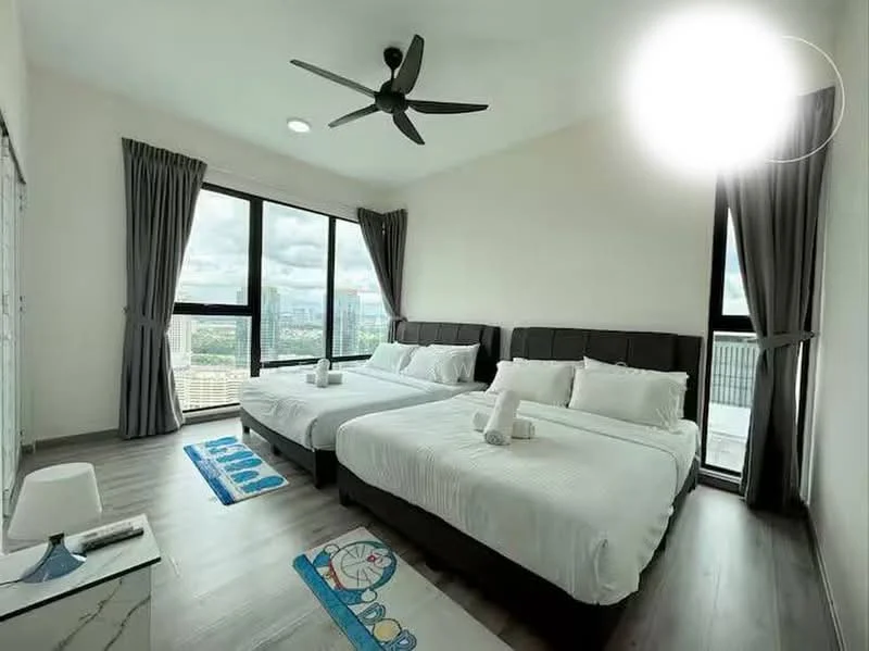 Bedroom features: two queen-size beds with upholstered headboards, white bedding with decorative pillows, wooden flooring, 5-blade ceiling fan with light, floor-to-ceiling windows, grey curtains, decorative area rug with geometric pattern, nightstand with lamp; style: modern; view: city.