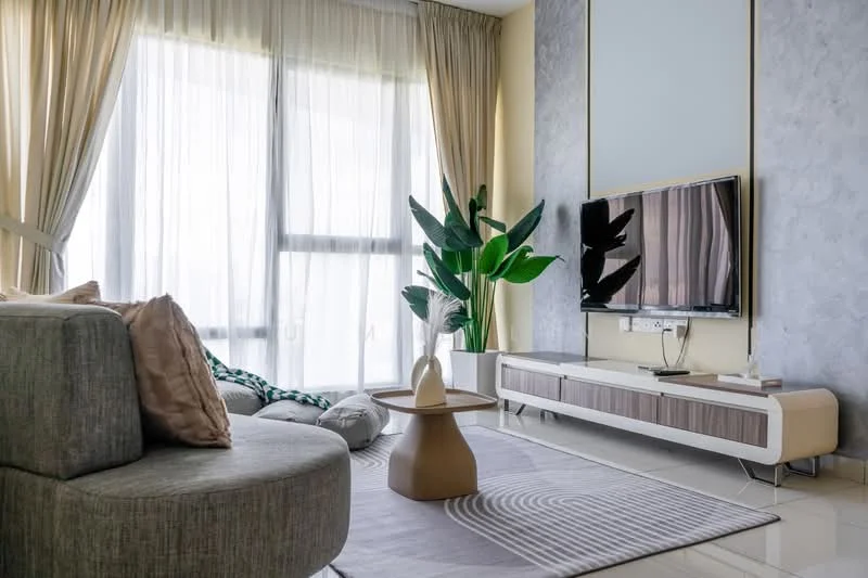 Living features: grey fabric sofa, decorative cushions, round coffee table, TV console with storage, wall-mounted TV, large floor-to-ceiling windows, sheer curtains, potted indoor plant, area rug with circular pattern, light-colored walls, polished tile flooring; style: modern; view: city.
