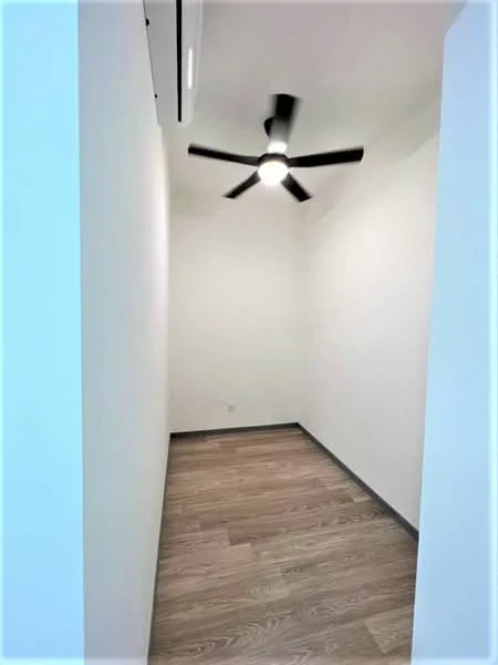 Room features: white painted walls, wooden flooring, 5-blade ceiling fan with light, wall-mounted air conditioning unit; style: modern.