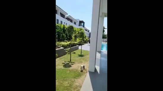 Exterior type: linked terrace house; features: manicured lawn, landscaped garden with shrubs, swimming pool visible in background, paved walkway, trees, modern architectural design, two-storey building, outdoor space; style: modern.