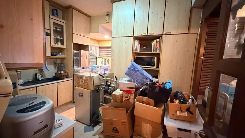 Kitchen features: wood cabinetry, black countertop, stainless-steel refrigerator, built-in oven, microwave, sink, tile flooring, multiple boxes and clutter, kitchen appliances, open shelving, window with blinds.