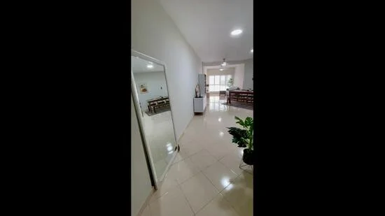 Room features: white painted walls, glossy tile flooring, recessed downlights, large mirror, open layout, dining area visible in background, natural light from windows, indoor plants; style: modern.