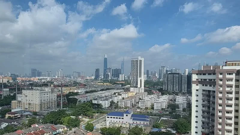 Exterior type: high-rise condominium; features: city skyline view, surrounded by urban landscape, mixed-use development, visible residential buildings, commercial buildings in the background, green spaces visible, clear blue sky, clouds, high-rise structures, low-rise structures; style: modern.