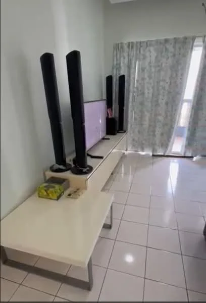 Living features: white walls, glossy tile flooring, large window with sheer curtains, TV on a white console table, two tall black speakers, decorative items on the console, light-colored wall, natural light from window; style: modern.
