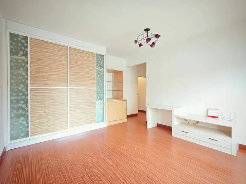 Living features: laminate flooring, white painted walls, sliding wardrobe with wooden panels, built-in wooden cabinet, ceiling light fixture with multiple bulbs, open layout, natural light from windows, neutral color scheme; style: modern.
