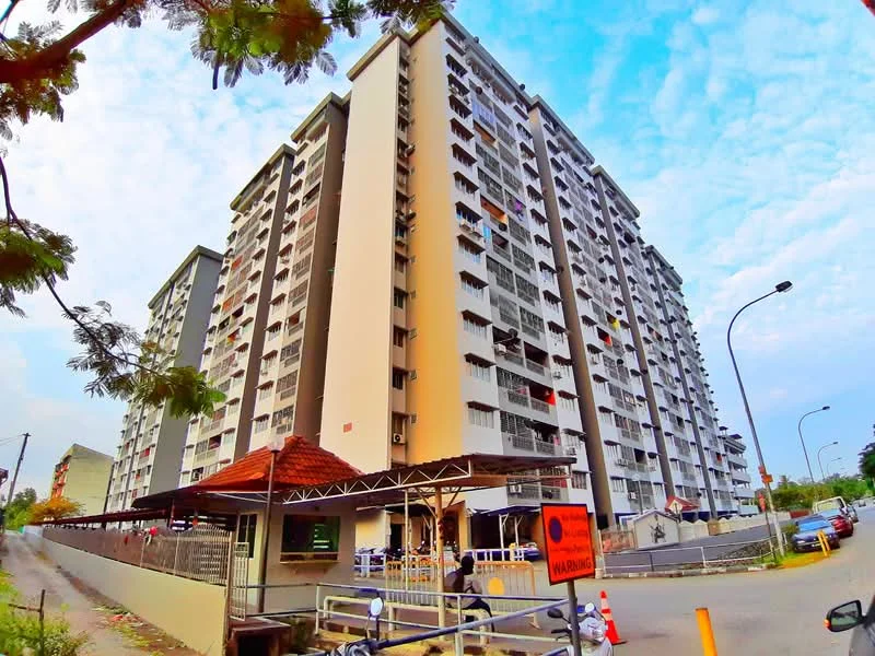Exterior type: mid-rise condominium; features: white painted facade, grey accent panels, balconies with railings, multiple storeys, manicured landscaping, entrance gate with guard house, parking area, surrounded by trees, street view, signage at entrance; style: modern.