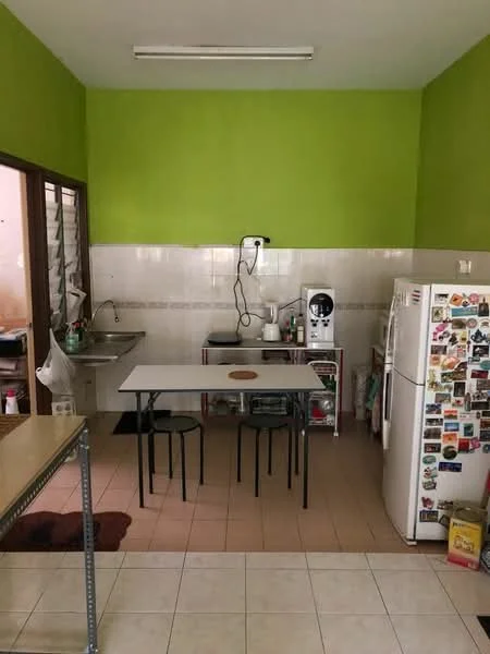 Kitchen features: green painted walls, white tiled backsplash, white ceramic tile flooring, single-bowl stainless-steel sink, chrome faucet, freestanding fridge, table with four black chairs, kitchen countertop, wall-mounted electrical outlet, window with grill, kitchen utensils on countertop.