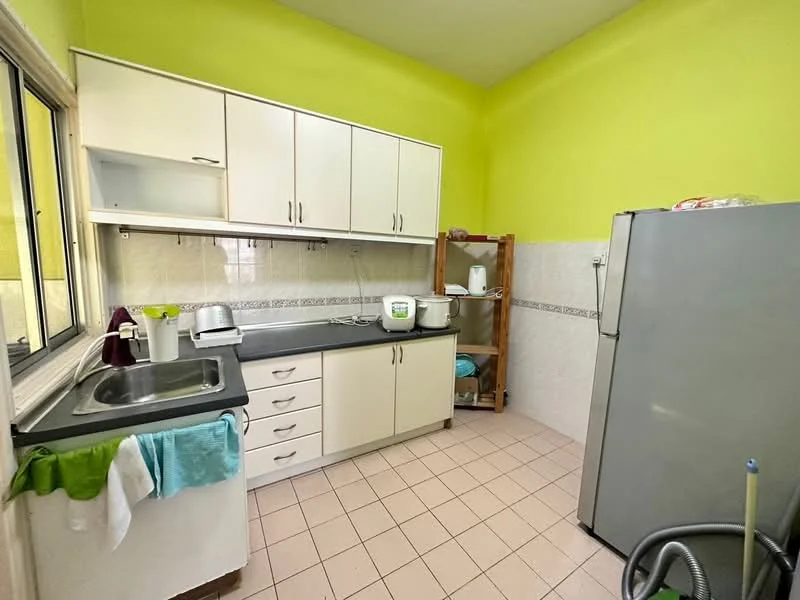 Kitchen features: green painted walls, white cabinetry with handles, black countertop, stainless-steel sink, chrome faucet, built-in shelving unit, white ceramic tile backsplash, tile flooring, refrigerator, kettle, toaster, dish rack.