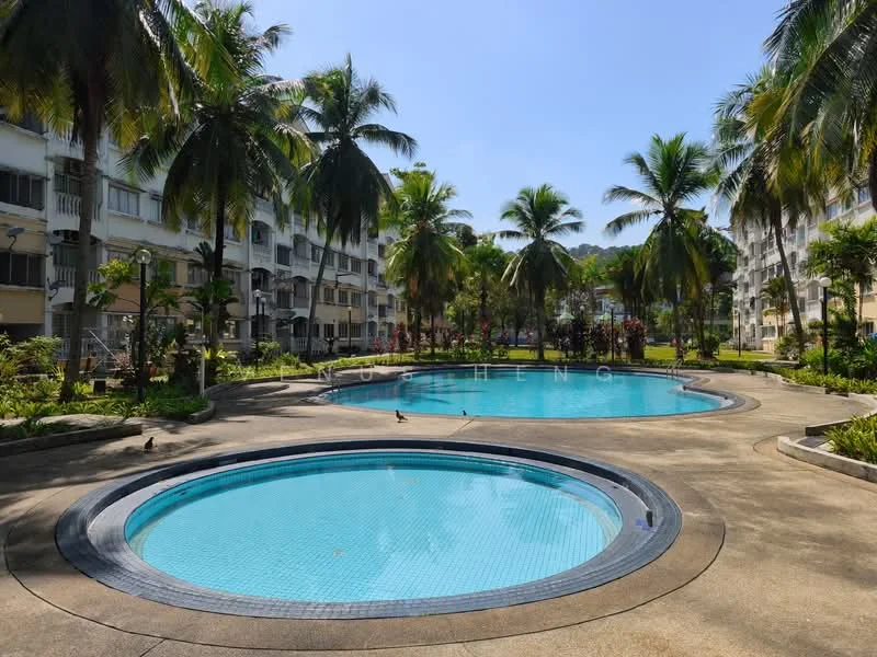 Exterior type: low-rise apartment block; features: two circular swimming pools, surrounded by palm trees, manicured landscaping, concrete pool deck, lounge area with sun loungers, lush greenery around pools, walkway around the pools, residential buildings in background; style: tropical-modern.