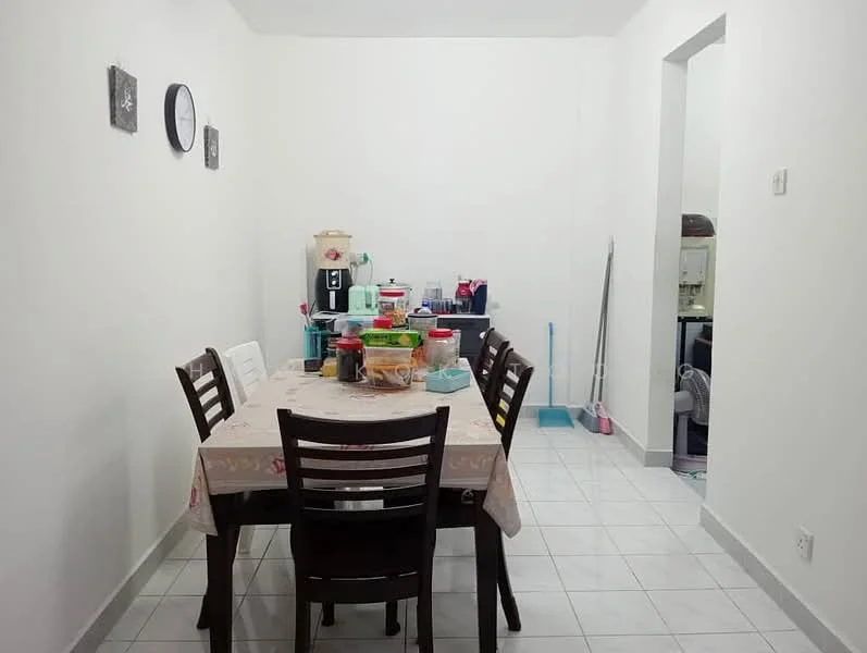 Dining features: white painted walls, ceramic tile flooring, dining table with tablecloth, 6 wooden dining chairs, wall clock, kitchen appliances on countertop, storage containers on table, cleaning supplies visible, open doorway to kitchen area.