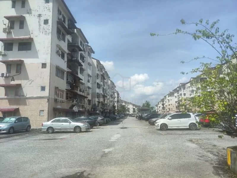 Exterior type: low-rise apartment block; features: multiple storey buildings, balconies on upper floors, parking lot with multiple vehicles, gravel road, surrounding greenery, clear blue sky; style: modern.