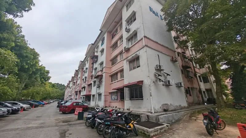 Exterior type: low-rise apartment block; features: pink painted facade, multiple air conditioning units on facade, ground-level parking area, motorcycles parked in front, trees surrounding the building, asphalt driveway, windows with metal grilles; style: modern.