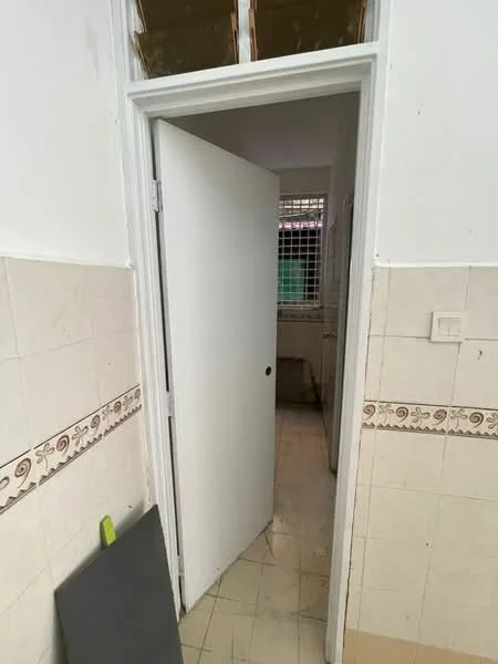 Room features: white painted walls, cream tiled flooring, plain white door, door frame, window with grid, decorative wall trim.