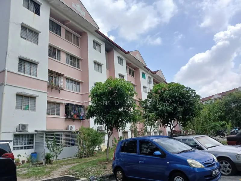 Exterior type: low-rise apartment block; features: pink and white painted facade, 3-storey building, balconies with metal railings, air conditioning units visible, landscaped area with small trees, parking lot with multiple vehicles, surrounded by greenery; style: modern.