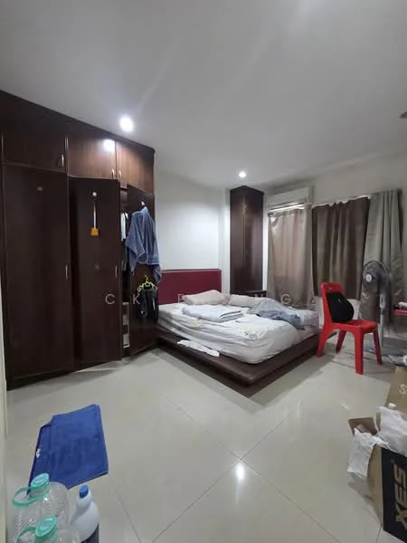 Bedroom features: queen-size bed with bedding, wooden wardrobe with sliding doors, red accent wall, cream painted walls, tile flooring, curtains in beige, ceiling fan, plastic chair in red, open shelving unit, bottled water on floor, boxes on floor; style: modern.