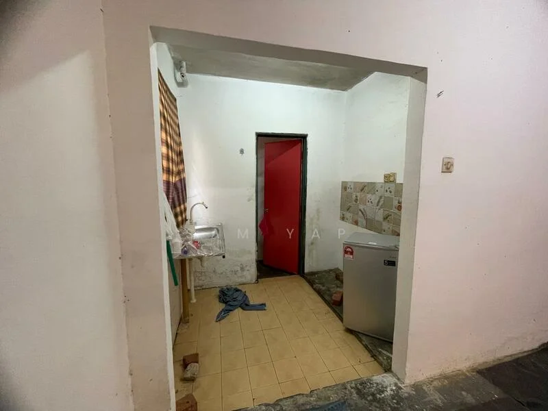 Room features: white painted walls, tile flooring, single-bowl stainless-steel sink, red door, fridge, window with sheer curtains, kitchenette area, wall tiles with decorative pattern.