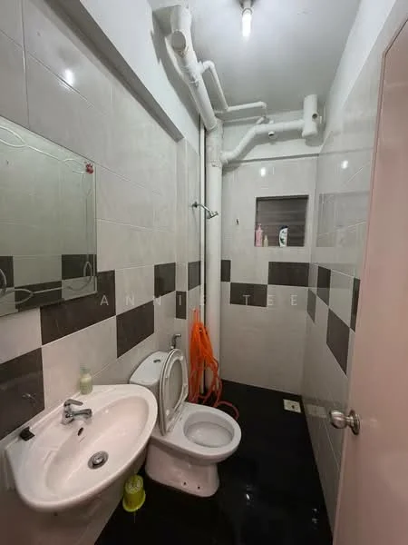 Bathroom features: white ceramic toilet, single-sink vanity with chrome faucet, mirror above sink, grey and white tiled walls, black tiled flooring, shower area with wall-mounted showerhead, exposed plumbing pipes, soap dispenser, toilet paper holder, cleaning supplies visible; style: modern.