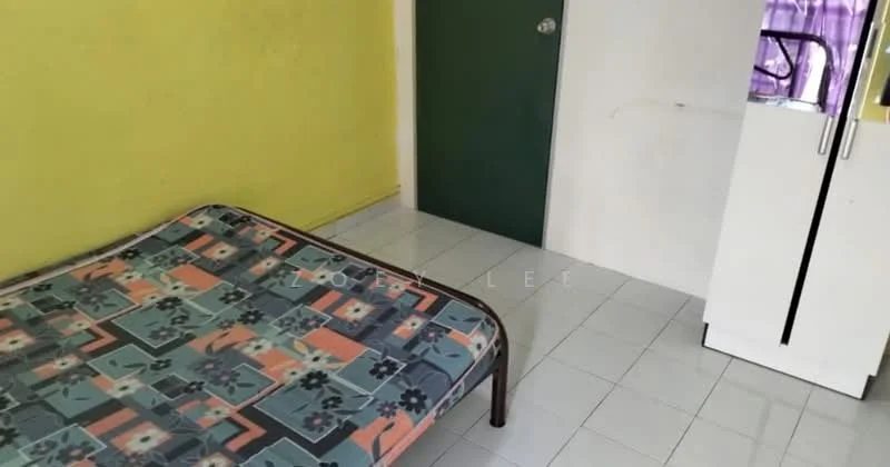 Room features: yellow painted walls, white tiled flooring, single bed frame, mattress with patterned cover, green door, refrigerator, window with purple curtains.