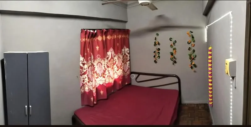 Bedroom features: single bed with maroon bedsheet, grey painted walls, red and white patterned curtains, wooden flooring, ceiling fan, built-in wardrobe in grey, decorative wall hangings, LED strip lighting.