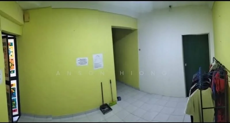 Room features: yellow painted walls, white tiled flooring, corner with doorway, door with green finish, light fixture on ceiling, coat rack with clothes, cleaning tools visible, empty space.
