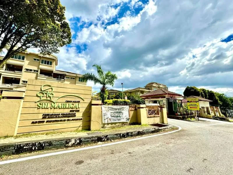 Exterior type: low-rise apartment block; features: cream painted facade, manicured lawn, palm trees, signage at entrance, guard house at entrance, paved driveway, surrounded by mature greenery; style: modern.