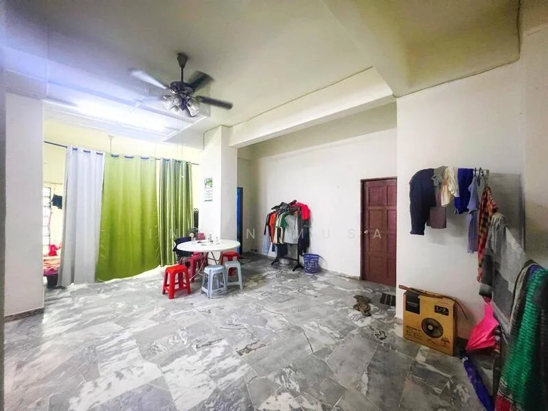 Room features: marble tile flooring, white painted walls, ceiling fan, dining table, red plastic chairs, green curtains, clothes hanging on wall, door, laundry basket.