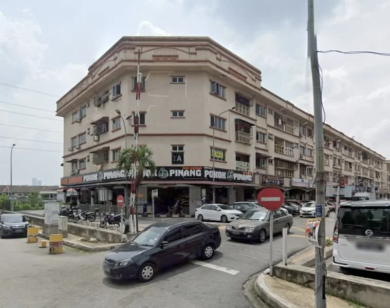Exterior type: shophouse; features: 3-storey building, cream painted facade, corner unit, signage for businesses on ground floor, balconies on upper floors, multiple windows, street-facing entrance, parking spaces visible, surrounded by road, urban setting; style: traditional.