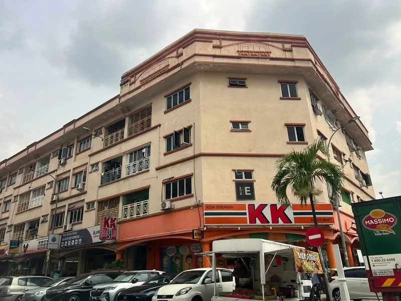 Exterior type: low-rise apartment block; features: cream painted facade, red accent trim, multiple balconies, ground floor retail spaces, signage for restaurants, large windows, palm tree in foreground, street view with parked cars; style: traditional.
