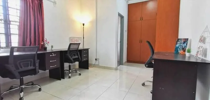 Study features: two study desks with chairs, wooden cabinetry, white painted walls, tile flooring, large windows with black grills, red curtains, floor lamp, decorative items on desk; style: modern.