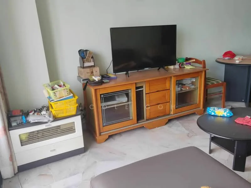 Living features: wooden TV console, flat-screen TV, marble flooring, air conditioning unit, green patterned cushion, wooden chair, decorative items on console, yellow storage basket, black coffee table, light grey walls.