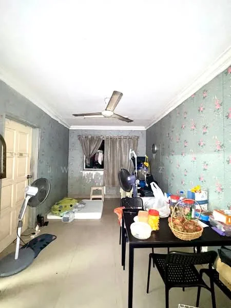 Room features: light grey wallpaper with floral pattern, cream painted ceiling, ceiling fan, window with sheer curtains, wooden door, tile flooring, black dining table, black plastic chairs, mattress on the floor, various items on the table, two standing fans, green mat on the floor.