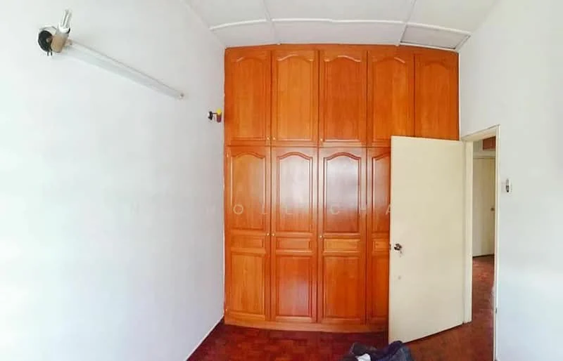 Room features: white painted walls, wooden wardrobe with multiple doors, brown tiled flooring, white door, ceiling with grid panels, light fixture on wall.