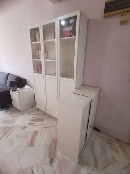 Room features: white cabinetry with glass doors, marble flooring with mixed patterns, light pink painted walls, small side table, books visible in cabinet, ambient lighting from cabinet, corner of a sofa visible; style: modern.