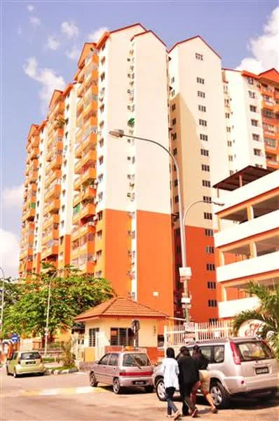 Exterior type: mid-rise condominium; features: orange and cream painted facade, multiple balconies, parking deck visible, landscaped entrance with trees, guard house at entrance, surrounded by mature greenery; style: modern.