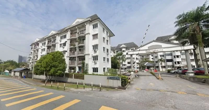Exterior type: low-rise apartment block; features: white painted facade, flat roof, approximately 4-storey, manicured lawn, palm trees, covered parking area, security boom gate, entrance with signage, surrounded by mature greenery; style: modern.