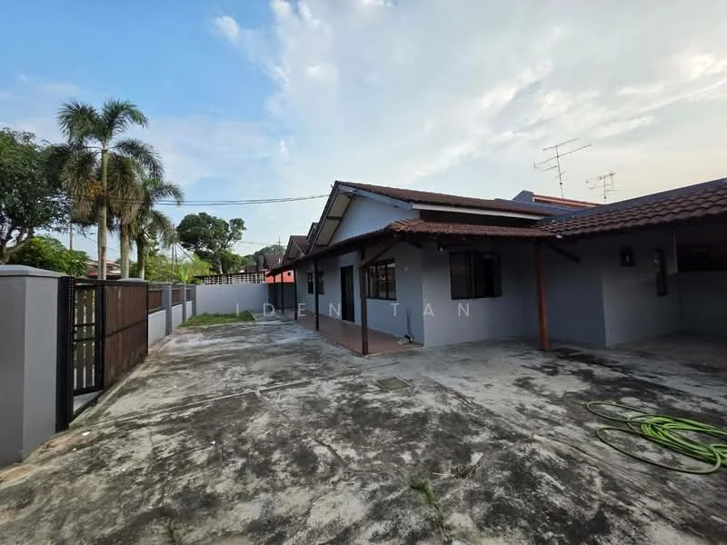 Exterior type: detached bungalow; features: single-storey, red tile roof, grey painted facade, manicured lawn, paved driveway, fenced perimeter, outdoor patio area, visible antenna, surrounded by greenery; style: modern.