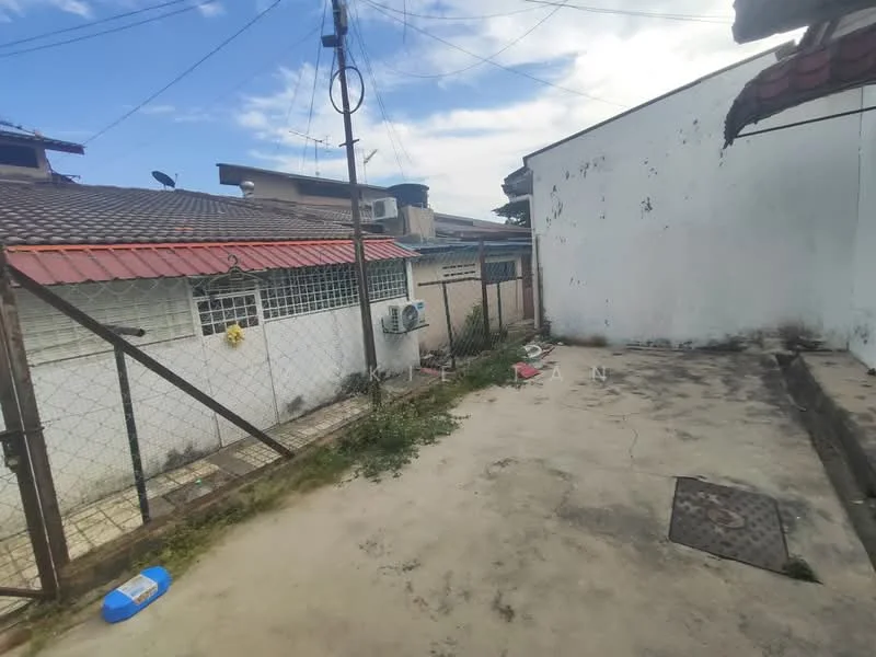 Exterior type: linked terrace house; features: concrete flooring, fenced yard, air conditioning unit mounted on wall, exposed brick wall, roof overhang, manicured grass patches, utility area with drainage, surrounding residential buildings, power lines visible, open sky view; style: traditional.