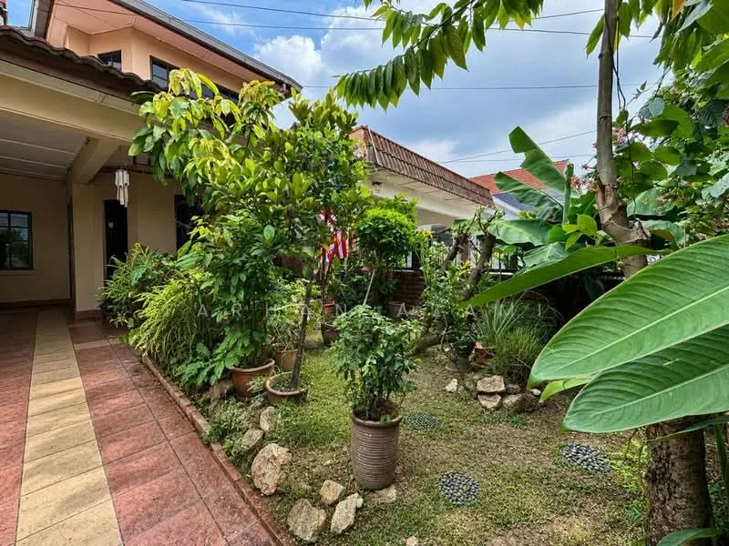 Exterior type: detached bungalow; features: manicured lawn, tropical landscaping, potted plants, stone-paved walkway, decorative stones, lush greenery, flagpole with flag, garden area with various plants; style: tropical-modern.