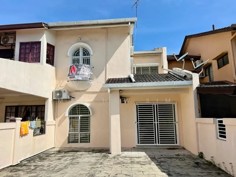 Exterior type: linked terrace house; features: cream painted facade, recessed balcony with decorative railing, flat roof, single-storey, manicured lawn, paved driveway, air conditioning unit on wall, security grille on doors, satellite dish on roof, laundry hanging on balcony; style: modern.