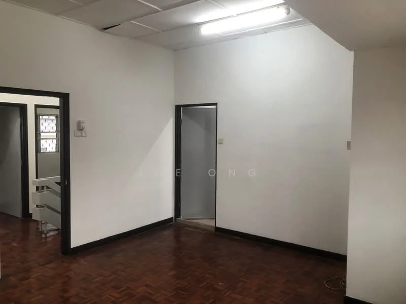 Room features: white painted walls, parquet wood flooring, fluorescent ceiling lights, door leading to another room, door leading to bathroom, corner of room with no visible furniture.