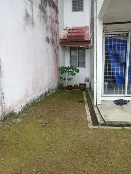 Exterior features: grass lawn, concrete pathway, exposed brick wall, red tiled roof, window with metal grille, potted plants, bare ground, adjacent wall.