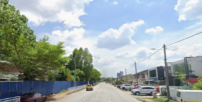 Exterior type: townhouse; features: tree-lined street, blue sky with clouds, residential buildings on both sides, parked cars along the street, fence along the left side, street lighting, sidewalk, greenery along the road; style: modern.