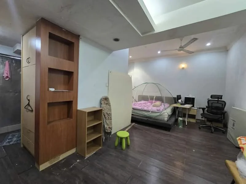 Bedroom features: queen-size bed with pink bedding, wooden wardrobe with open shelving, wooden bedside table, office desk with chair, ceiling fan, laminate flooring, white painted walls, decorative wall light, mosquito net over bed, green stool; style: modern.