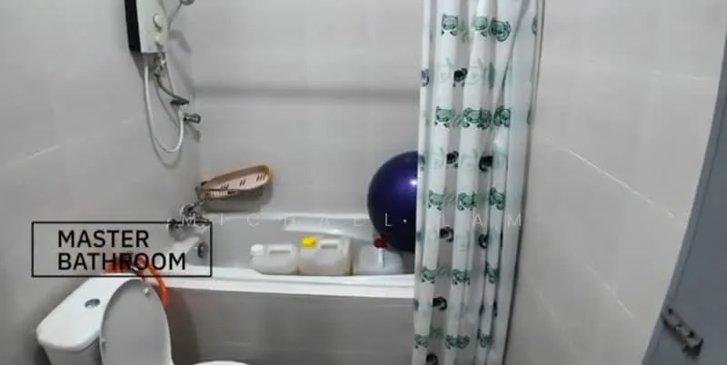 Bathroom features: bathtub with shower curtain, toilet, wall-mounted shower head, white tiled walls, light grey tiled flooring, shower curtain with pattern, soap dispenser, blue exercise ball, plastic storage containers.
