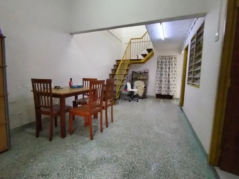 Room features: dining table with four wooden chairs, staircase leading to upper floor, green terrazzo flooring, white walls, window with sheer curtains, wall-mounted air conditioning unit, decorative wall paneling, light fixture on ceiling.
