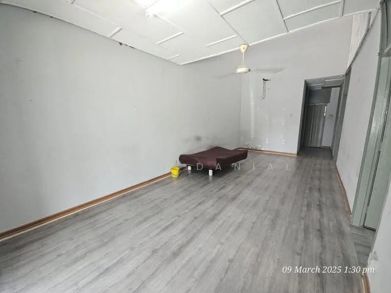 Room features: grey painted walls, laminate flooring, ceiling fan, single bed mattress on the floor, wooden skirting, no visible windows or doors.